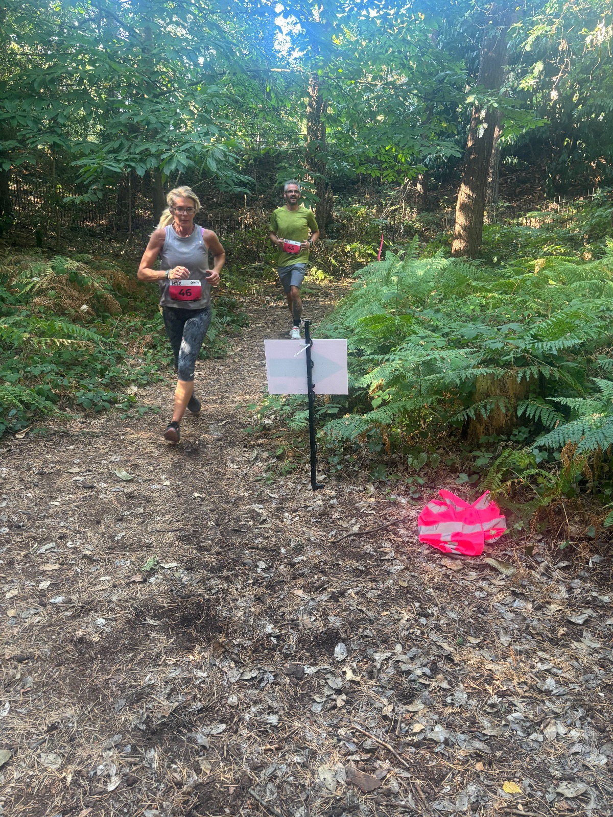 Runners on a woodland trail lined with ferns