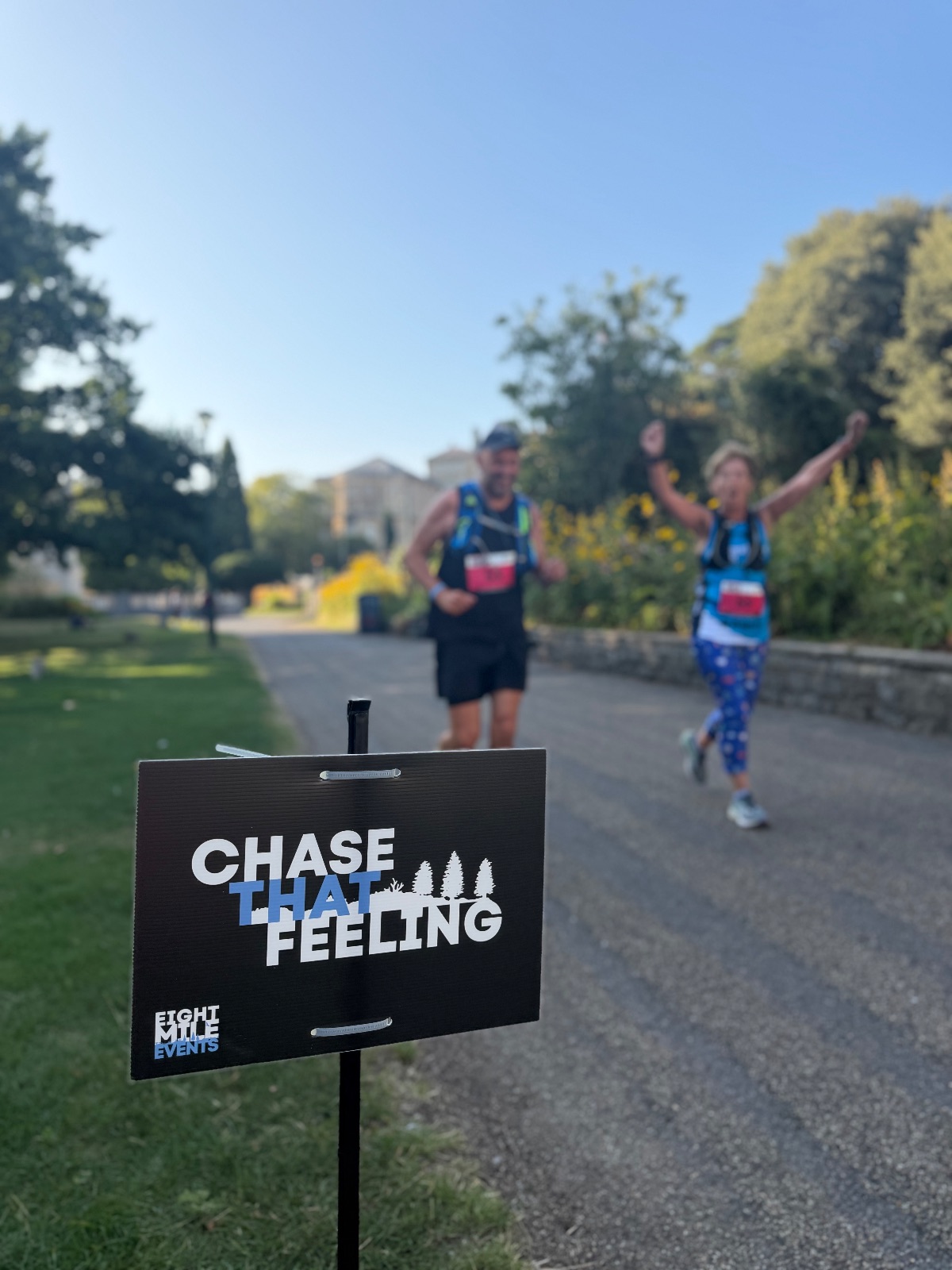 Chase that feeling course sign with runners celebrating behind