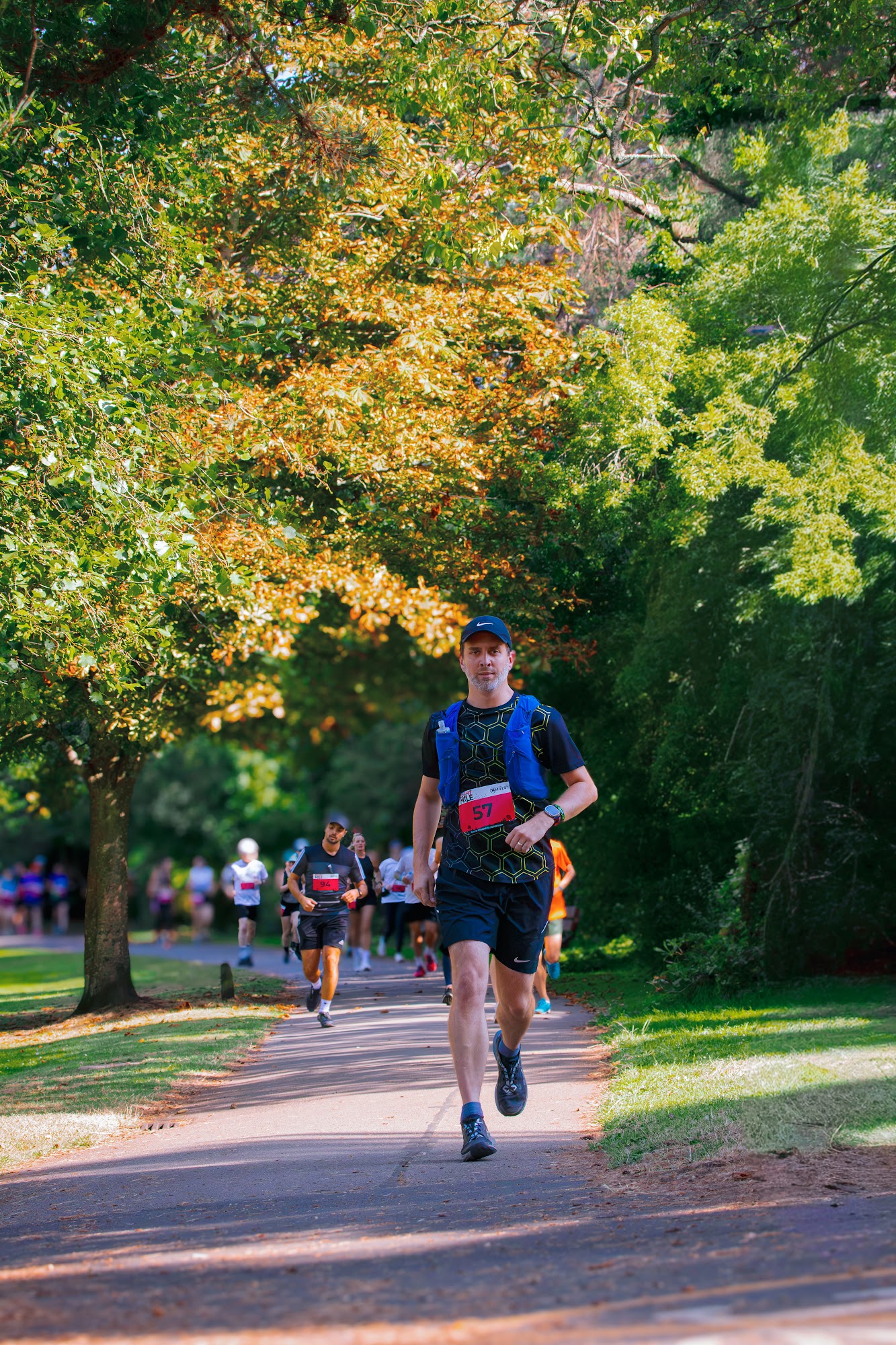 Lone runner on a dramatic tree-lined path with autumn foliage — Jess Photography